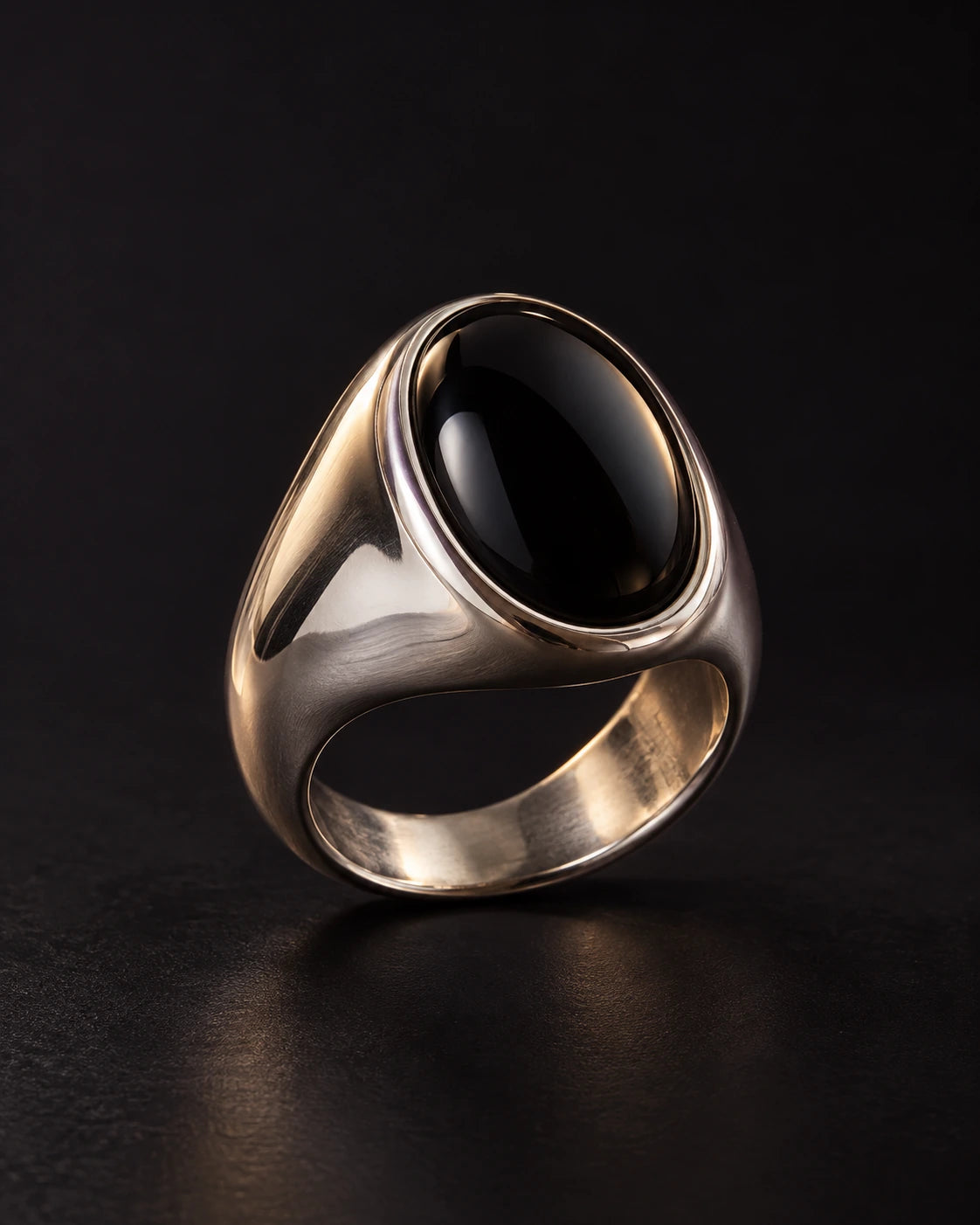 Silver-tone ring with a polished black oval stone in a smooth bezel setting on a dark background.